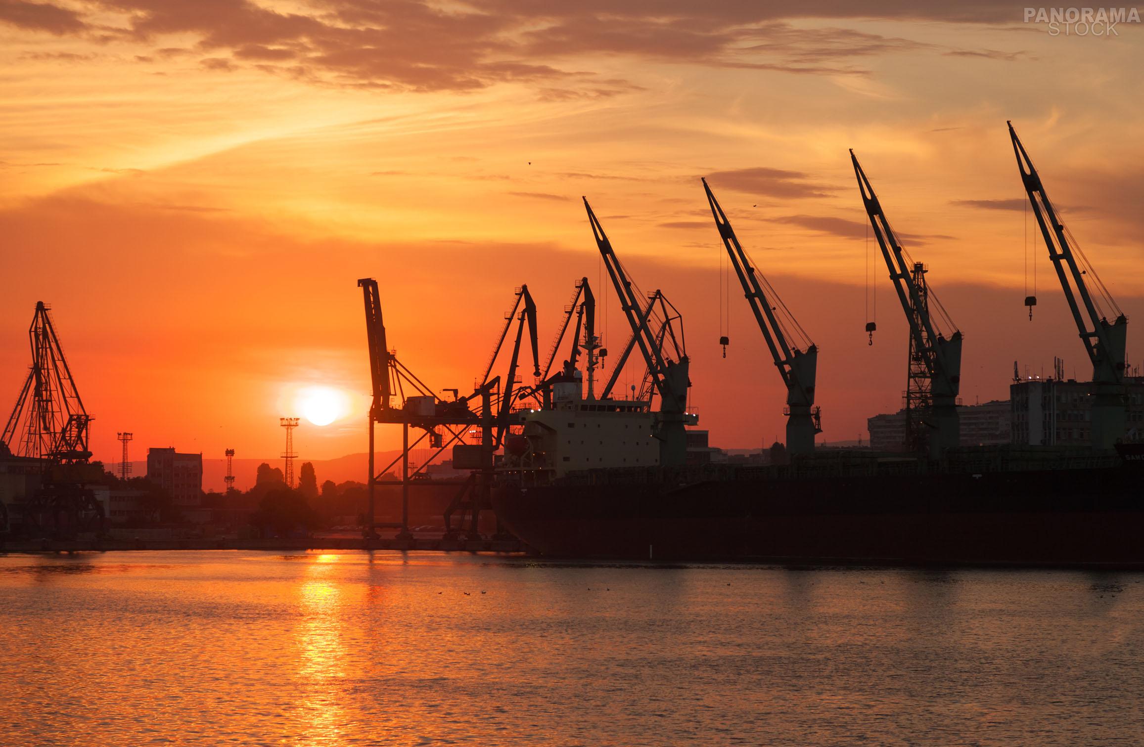 Silhouettes of cranes and industrial cargo ships in Varna port at ...